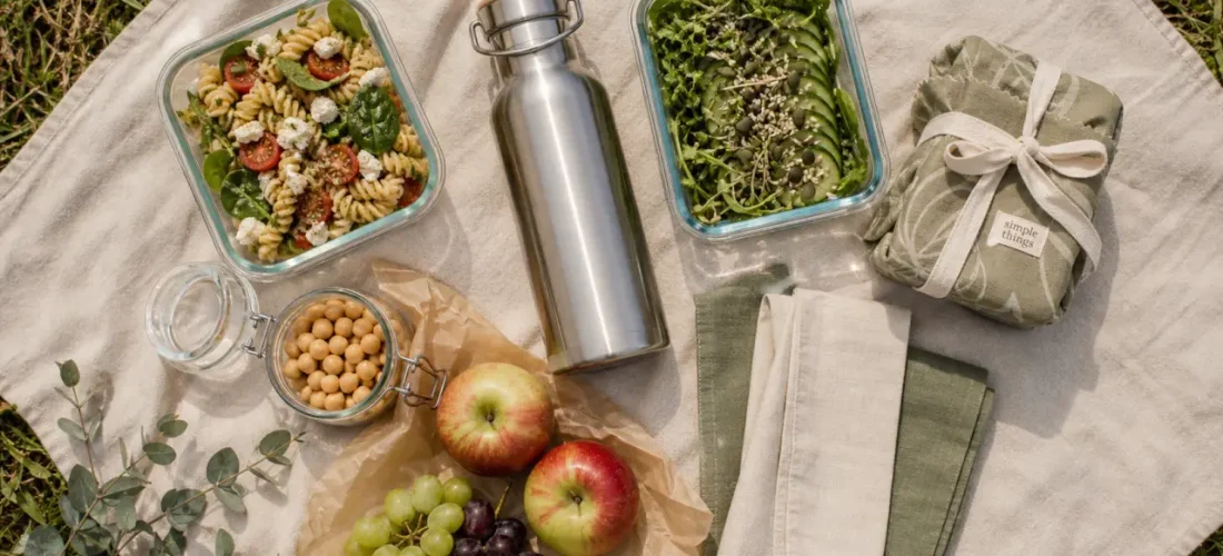 Pique nique zéro déchet : gourde inox et boîtes en verre sur nappe